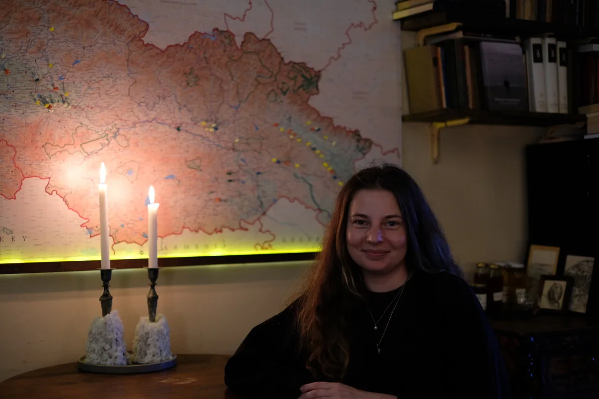 Aleksandra “Sasha” Novikova seated beside two candles with a map of Georgia behind her.