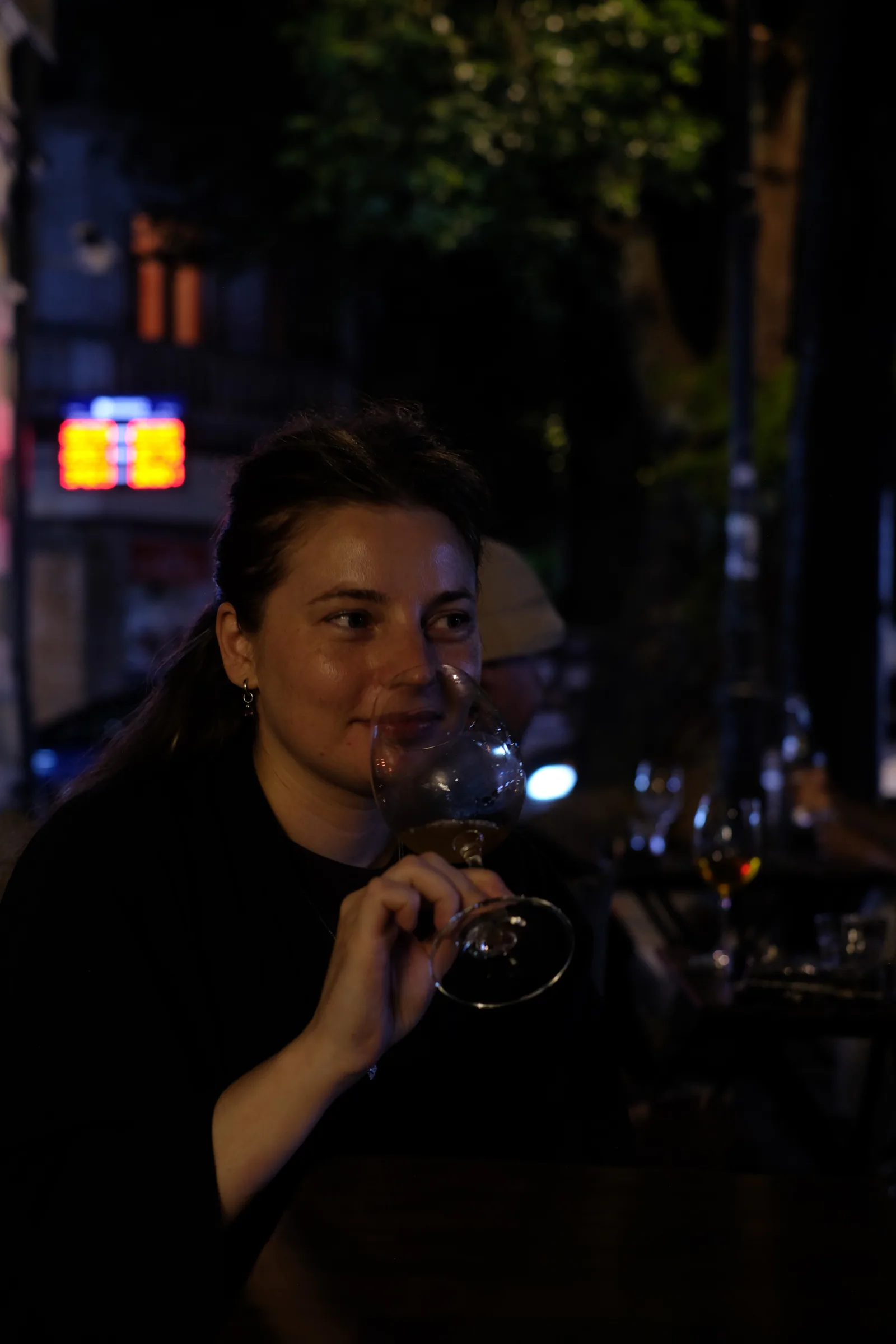 Aleksandra “Sasha” Novikova holding a wine glass at the table outside MIDI.