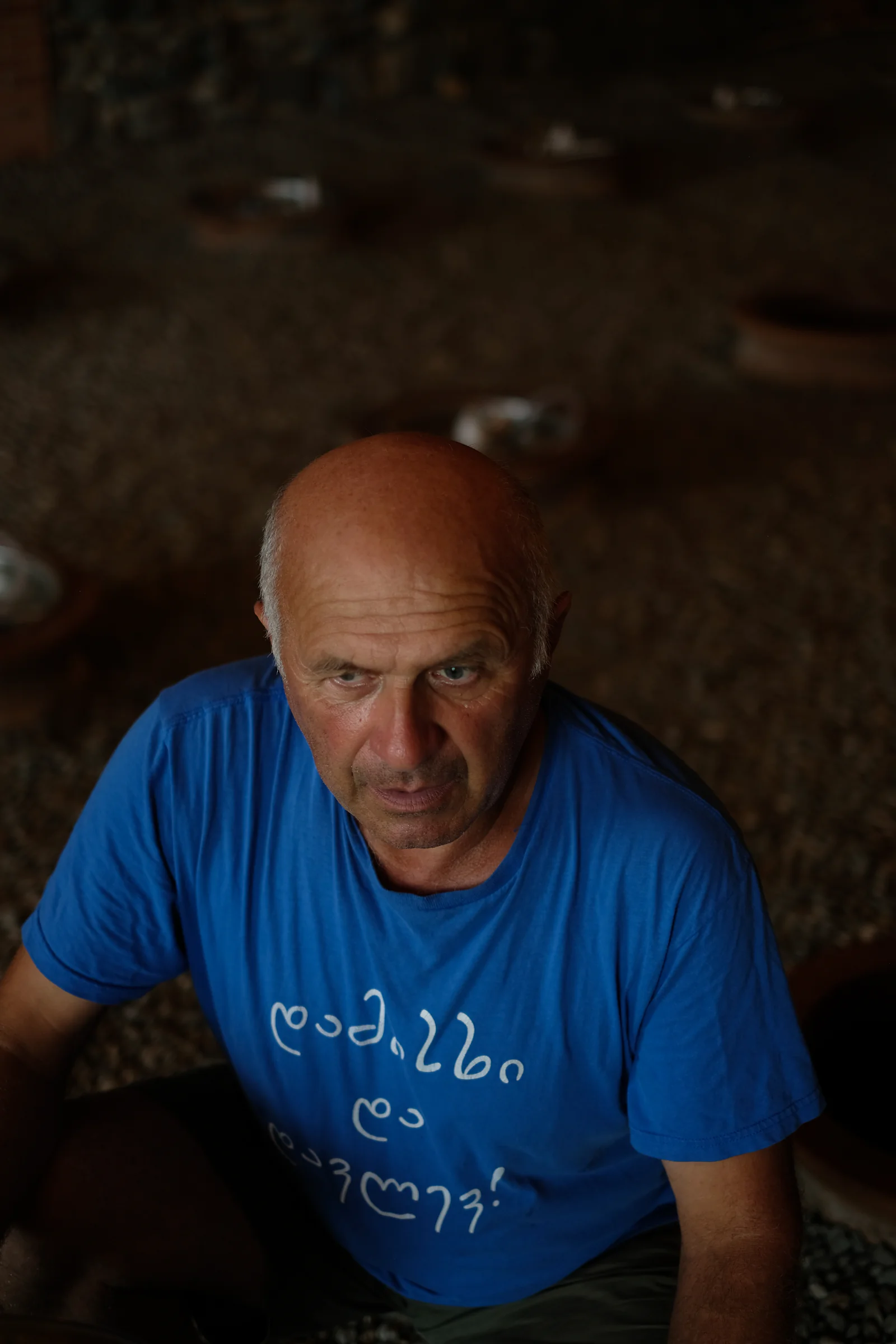 Baia's father seated in the new qvevri cellar, wearing a blue T-shirt.