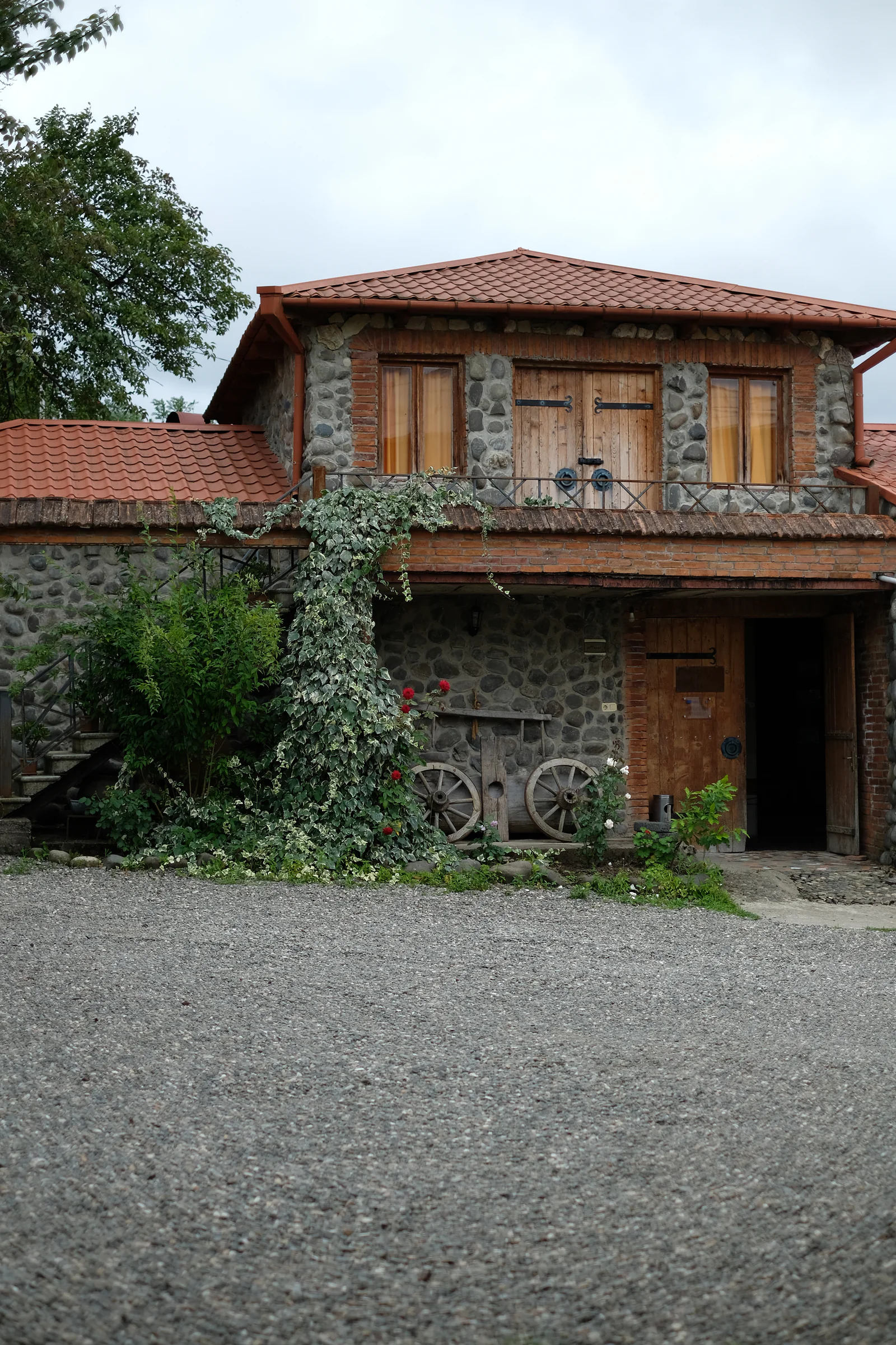 The stone and brick exterior of Baia's Wine, with wooden doors, red roofs and climbing plants.