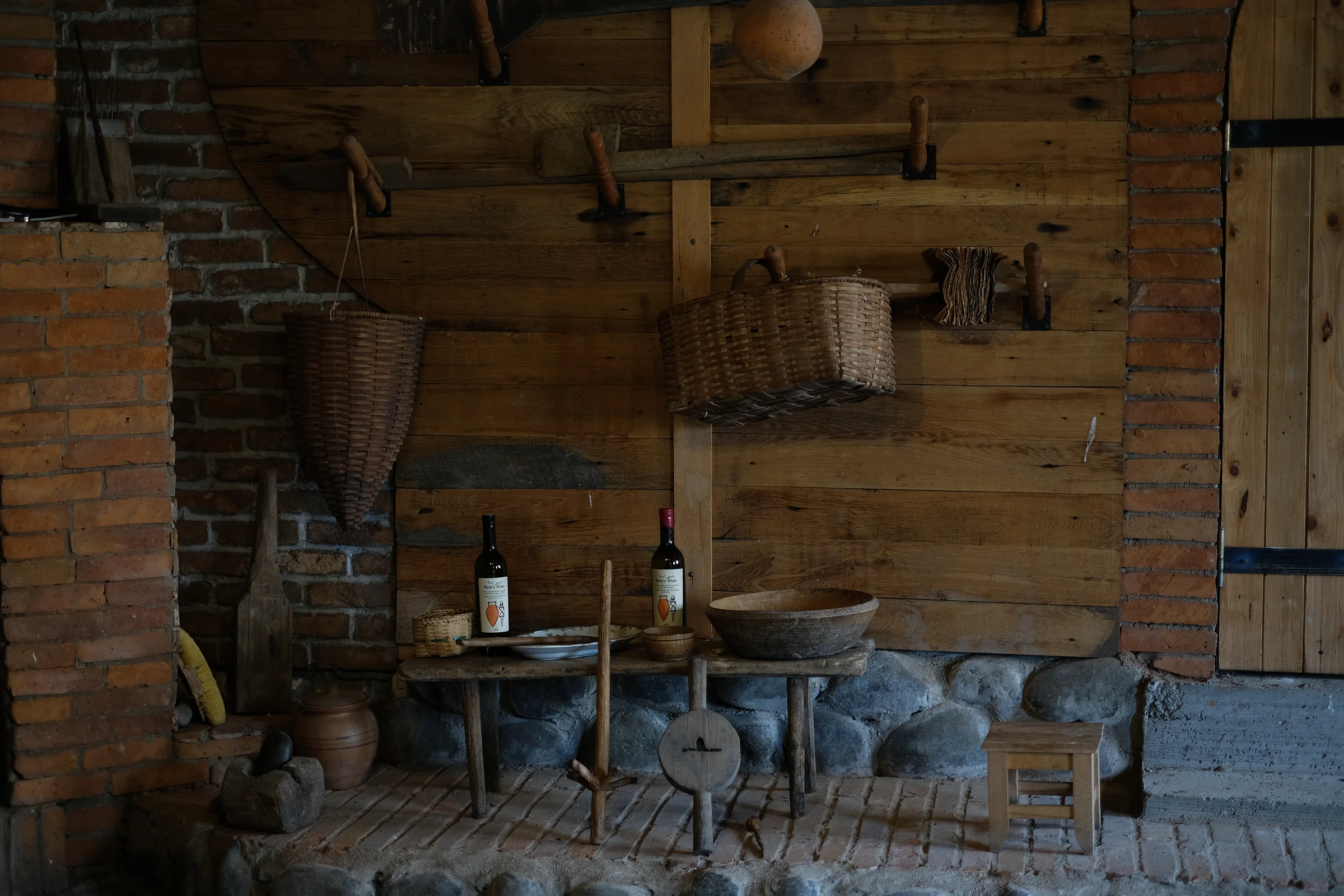 Winemaking tools, baskets and two bottles displayed against a wooden wall in the family's small museum.