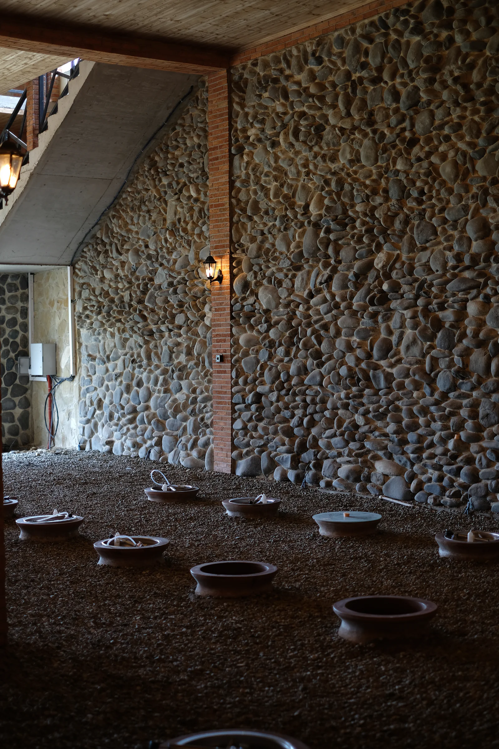 Qvevri set into the gravel floor beneath a staircase in the new cellar.