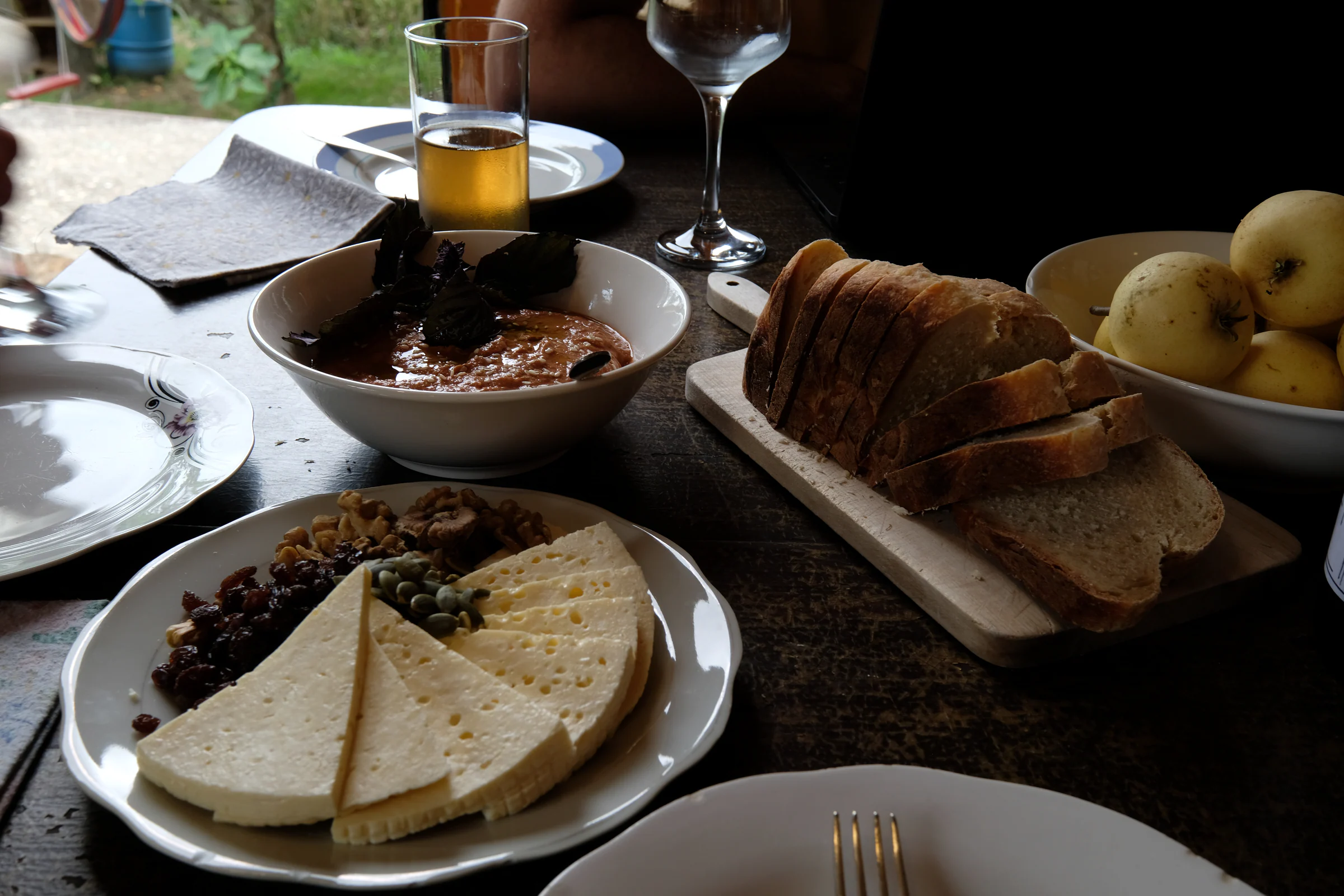 Imeretian cheese, bread, walnuts, raisins, seeds and a red sauce arranged on the table.