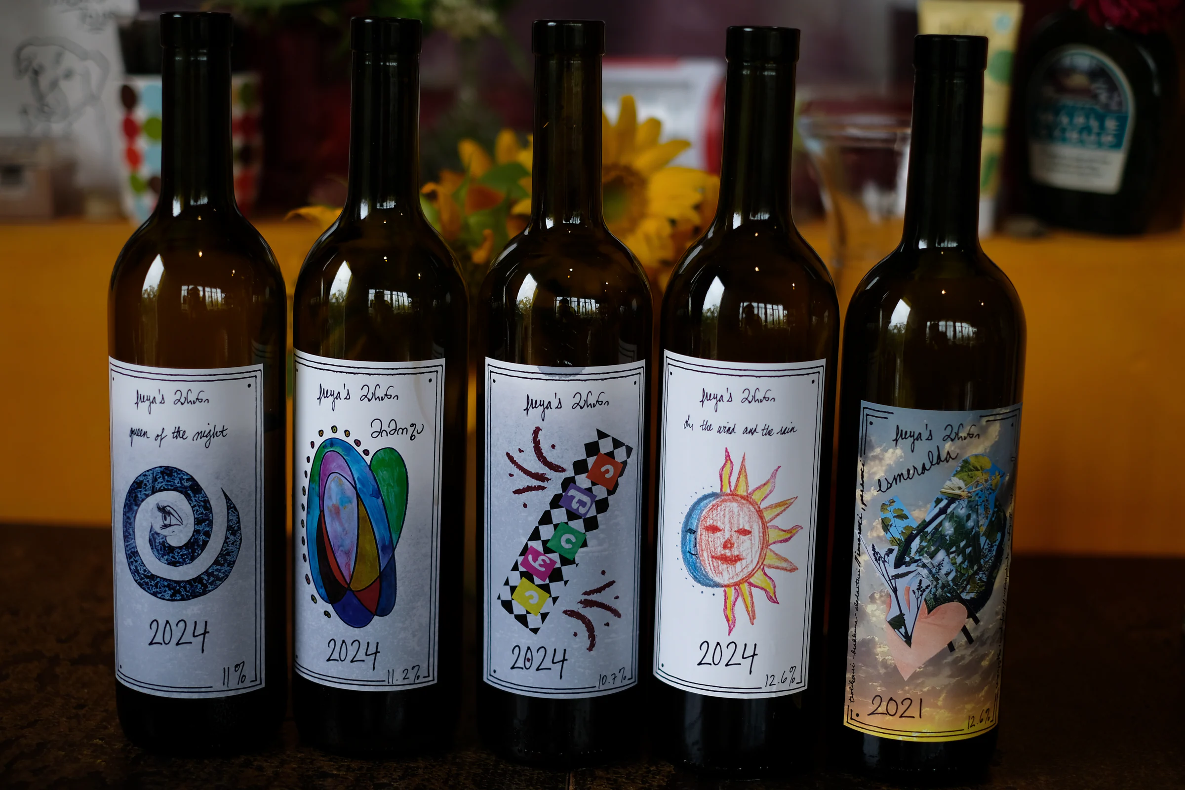 Five bottles of Freya's Marani wine with handmade labels lined up on a table.
