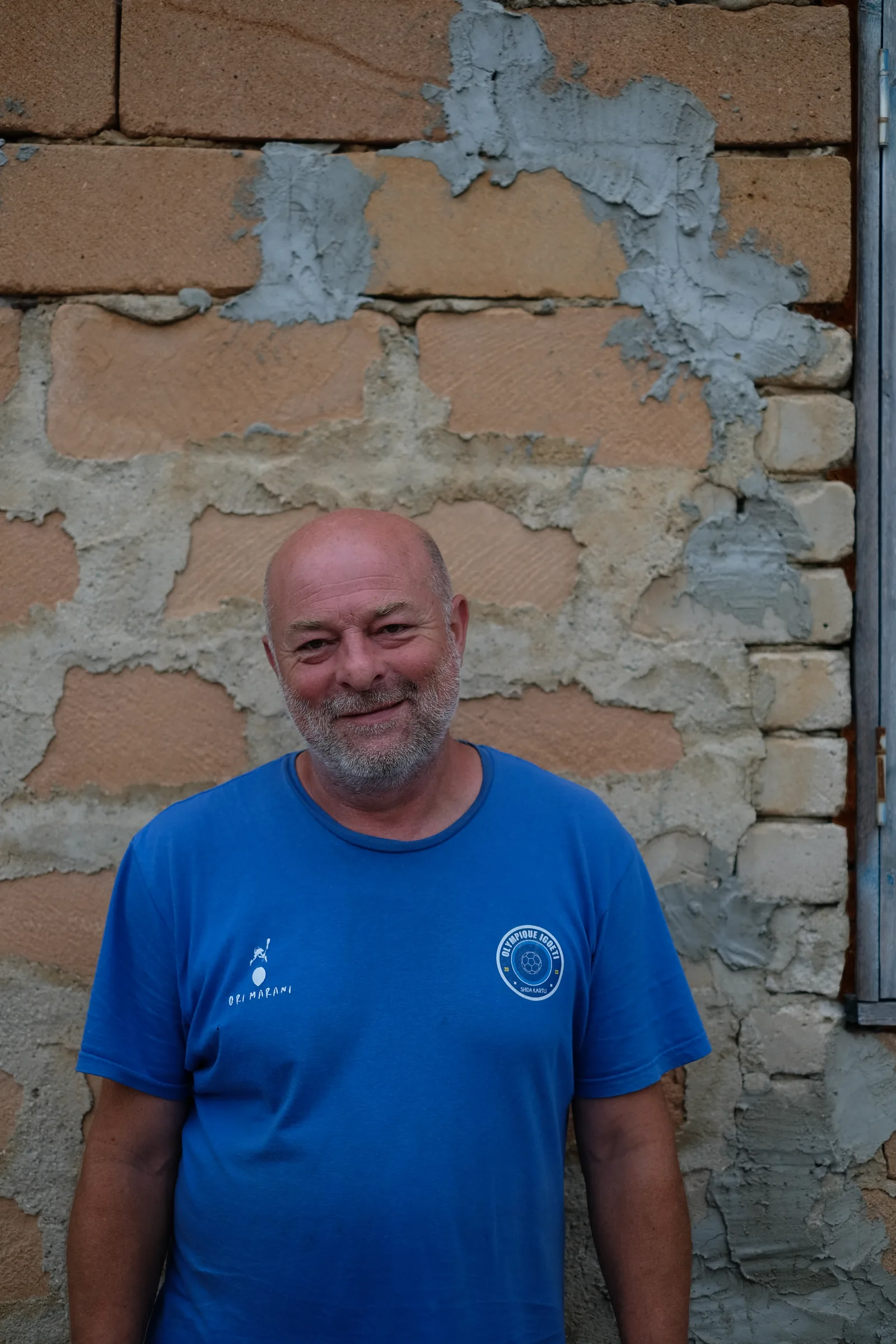 Ramaz Nikoladze standing in front of a brick wall outside the winery.